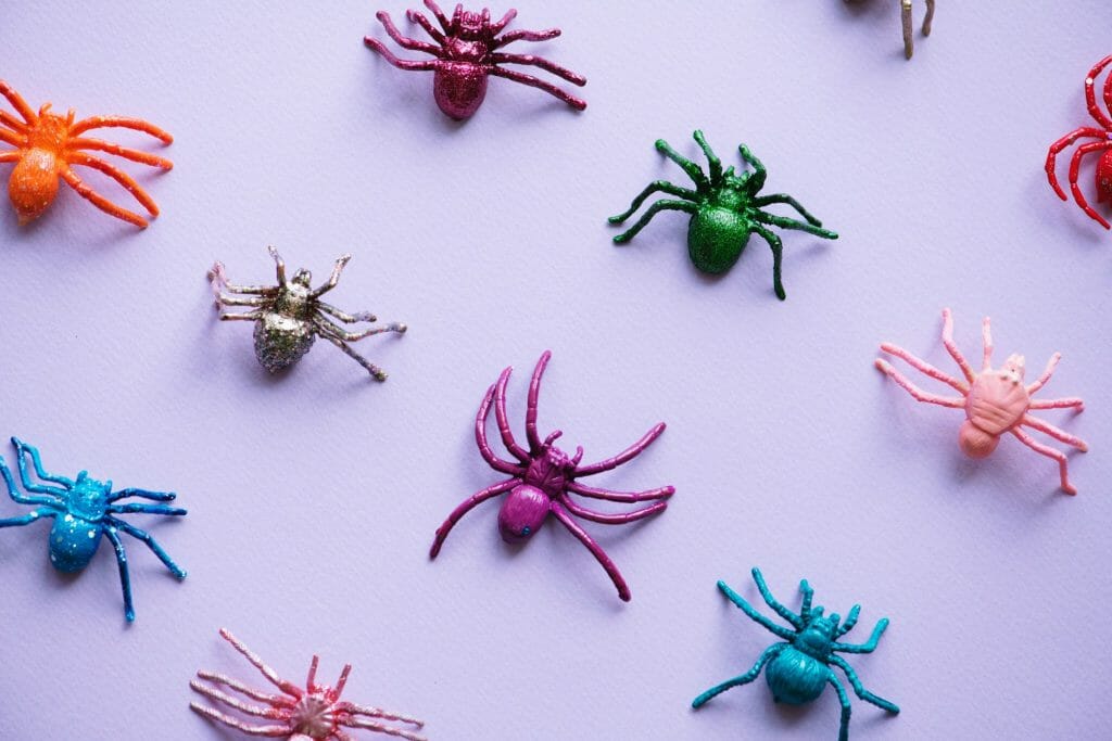 Colourful toy spiders on a pink background